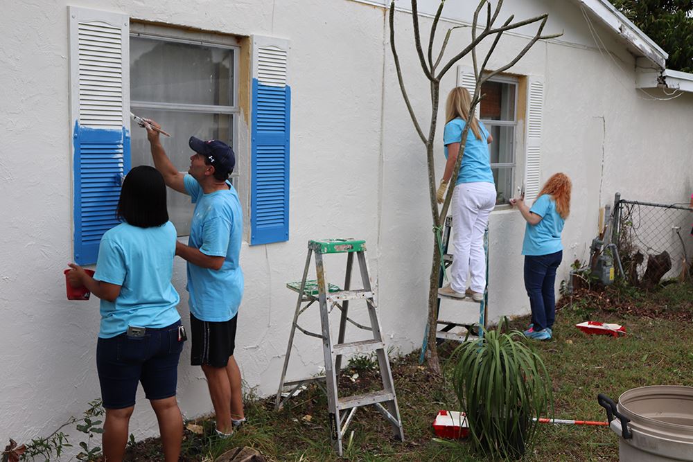 Photos of volunteers painting houses at NET event
