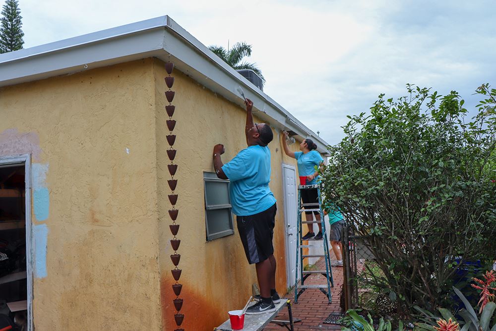 Photos of volunteers painting houses at NET event