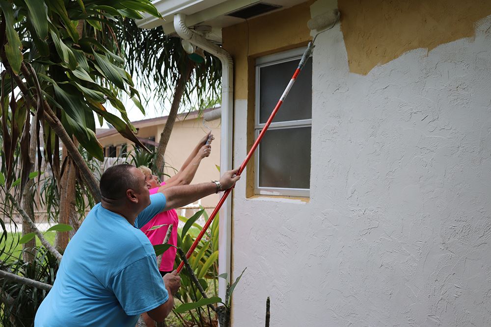Photos of volunteers painting houses at NET event