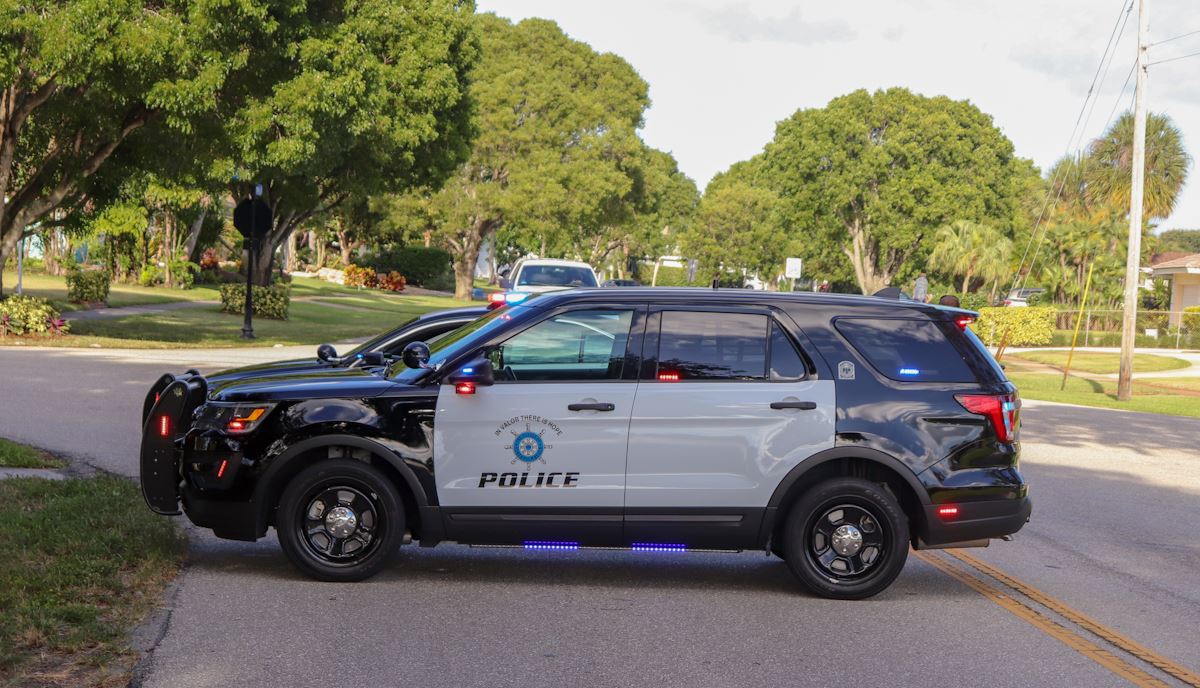 Police car in road with emergency lights on, blocking traffic.